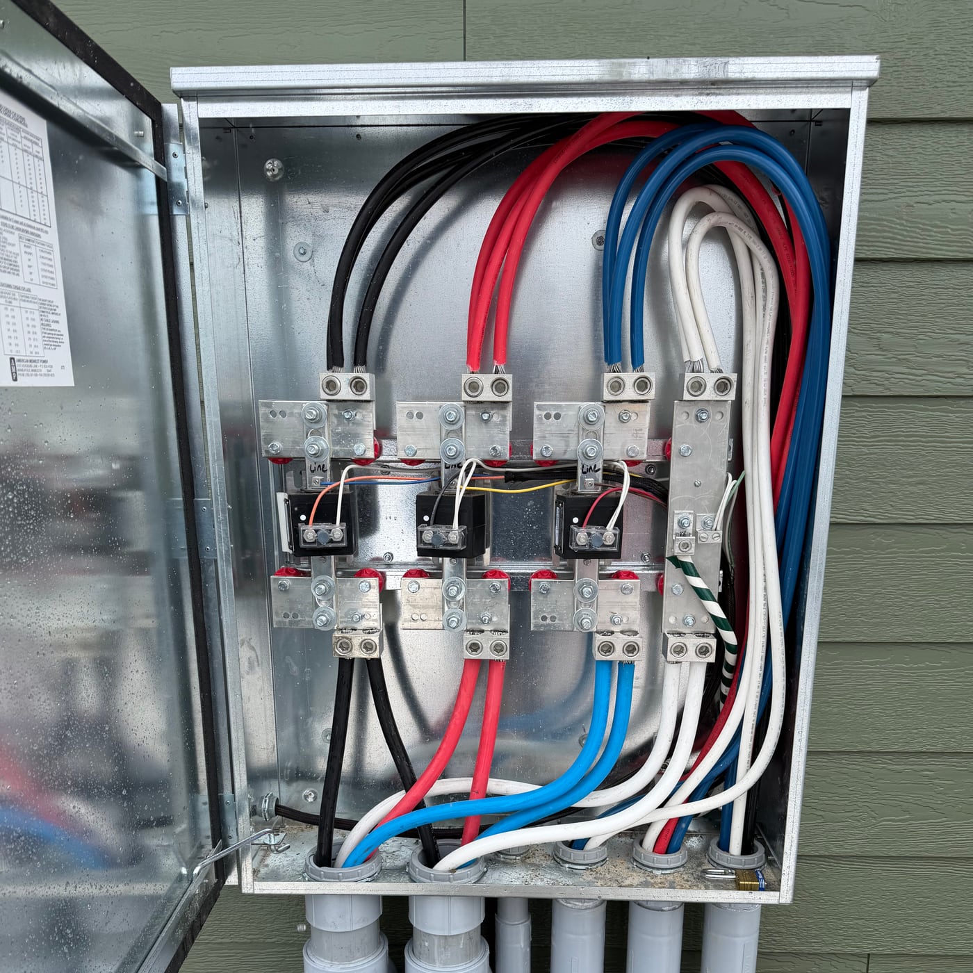 Color-coded conduit and bus bar wiring inside a newly installed electrical service panel